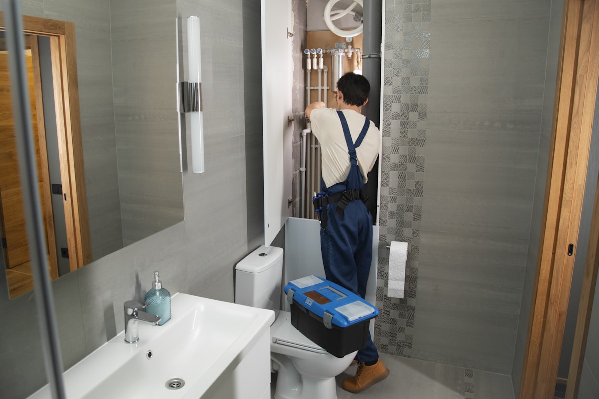 Certified plumber repairing a pipe joint under a kitchen sink